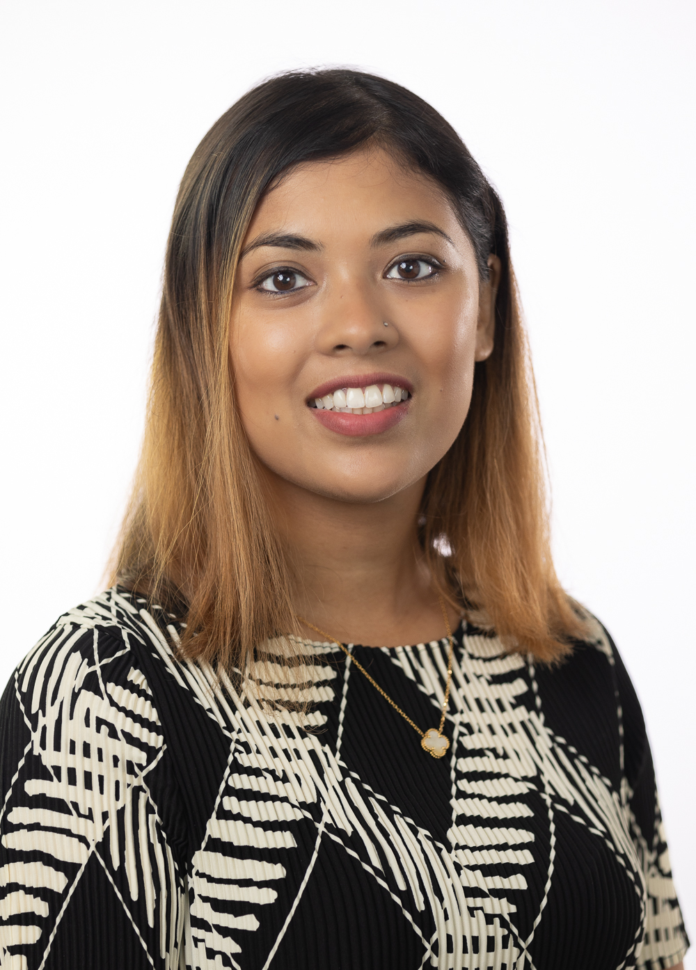 Dietitian Ayesha Kabir, MS, RD, LD, CNSC smiling in front of a white backdrop. She is wearing a black sweater with a white criss-cross pattern.