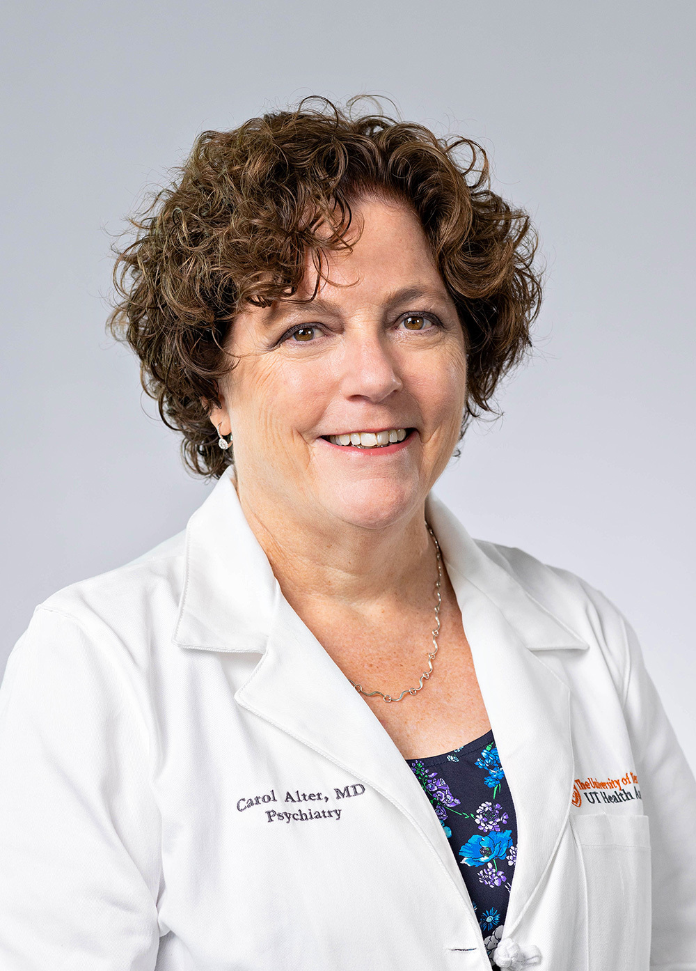 Dr. Carol L. Alter wearing a white coat and smiling in front of a white backdrop.