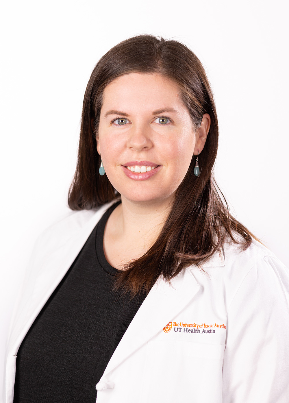 Charley Peterson wearing a white coat and smiling in front of a white backdrop.