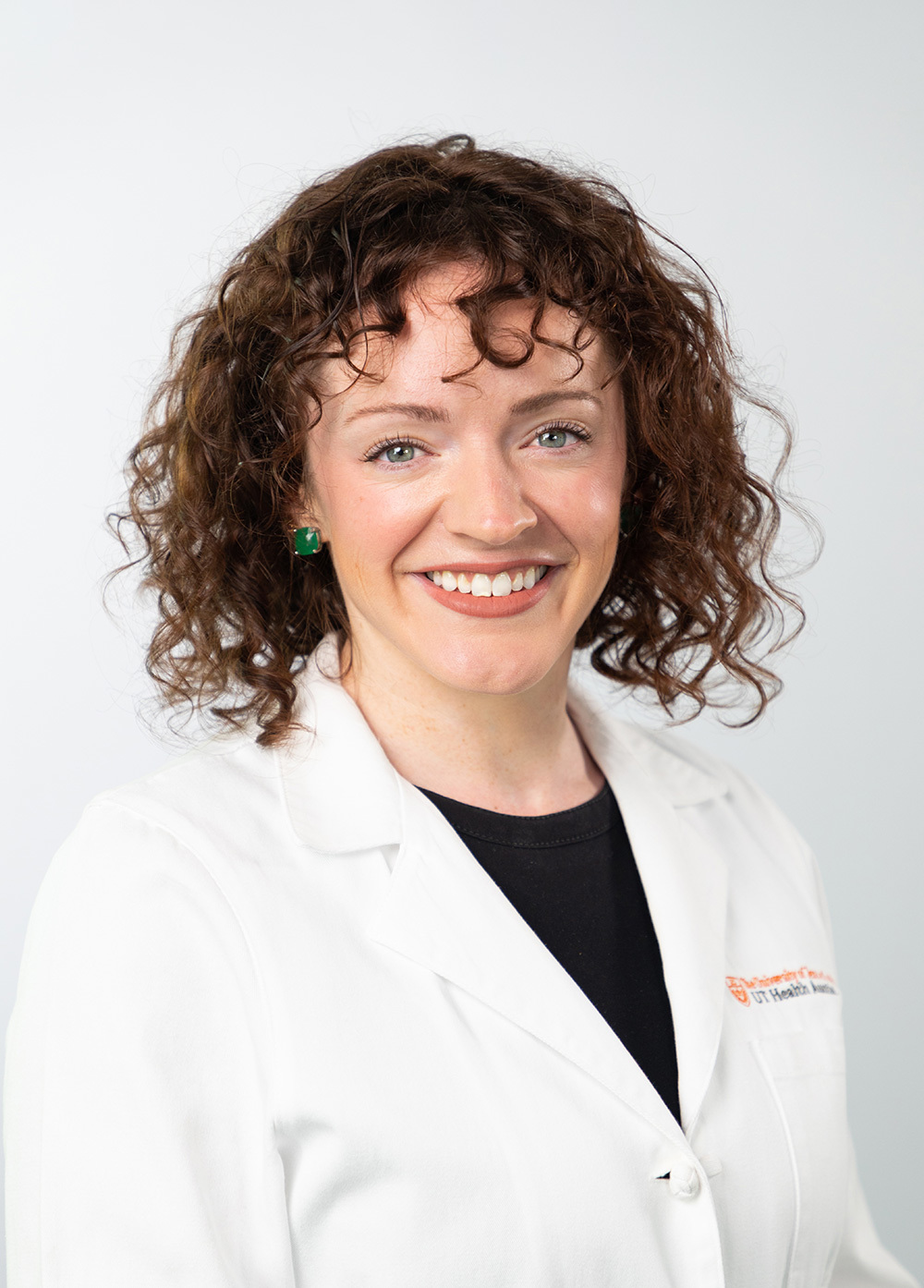 Dr. Christine Bartow wearing a white coat and smiling in front of a white backdrop.