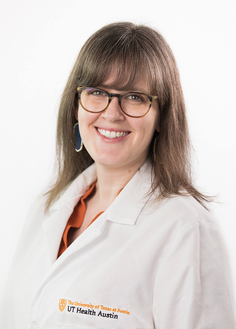 Dr. Corinne Jones wearing a white coat and smiling in front of a white backdrop.