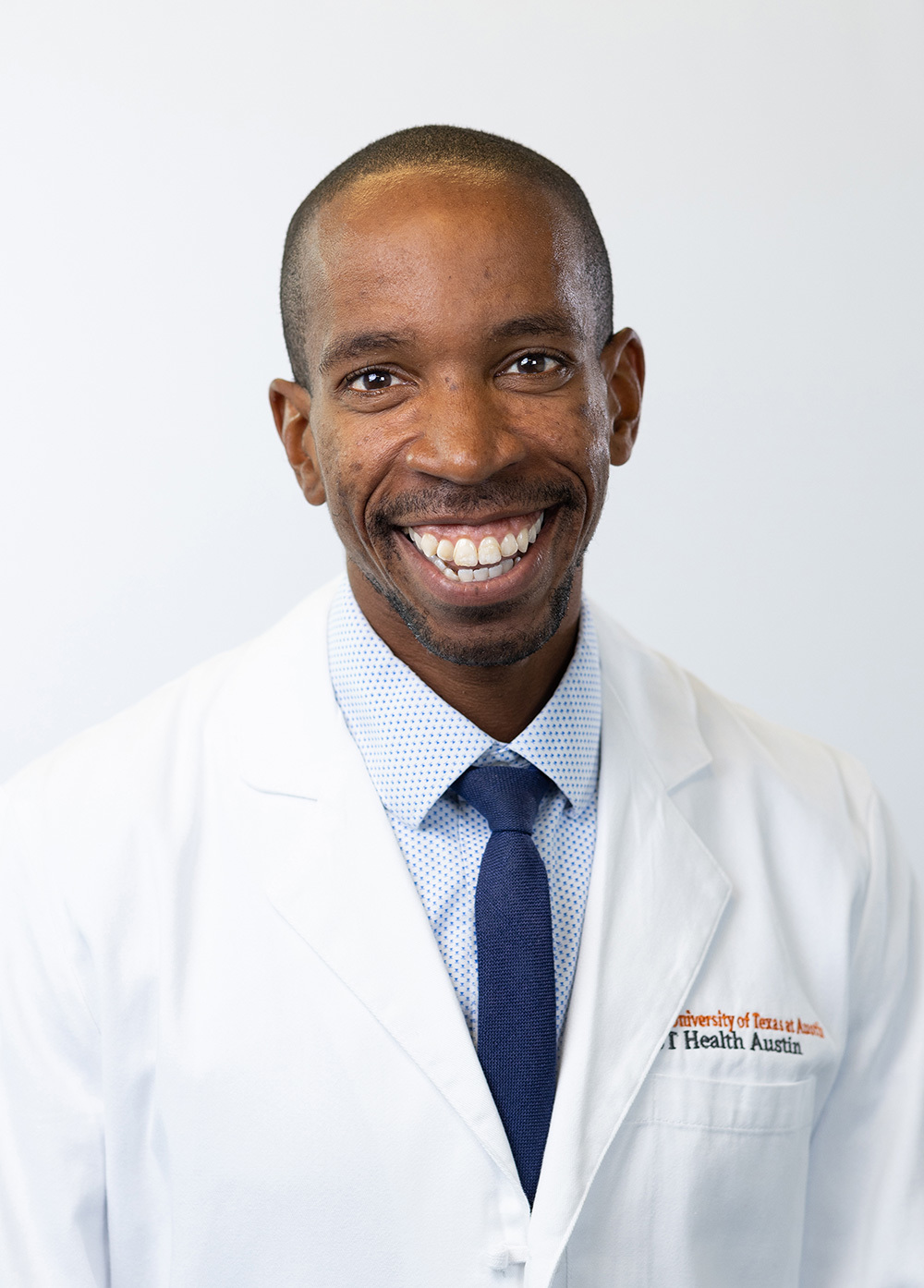 Dr. Duriel Hardy wearing a white coat and smiling in front of a white backdrop.