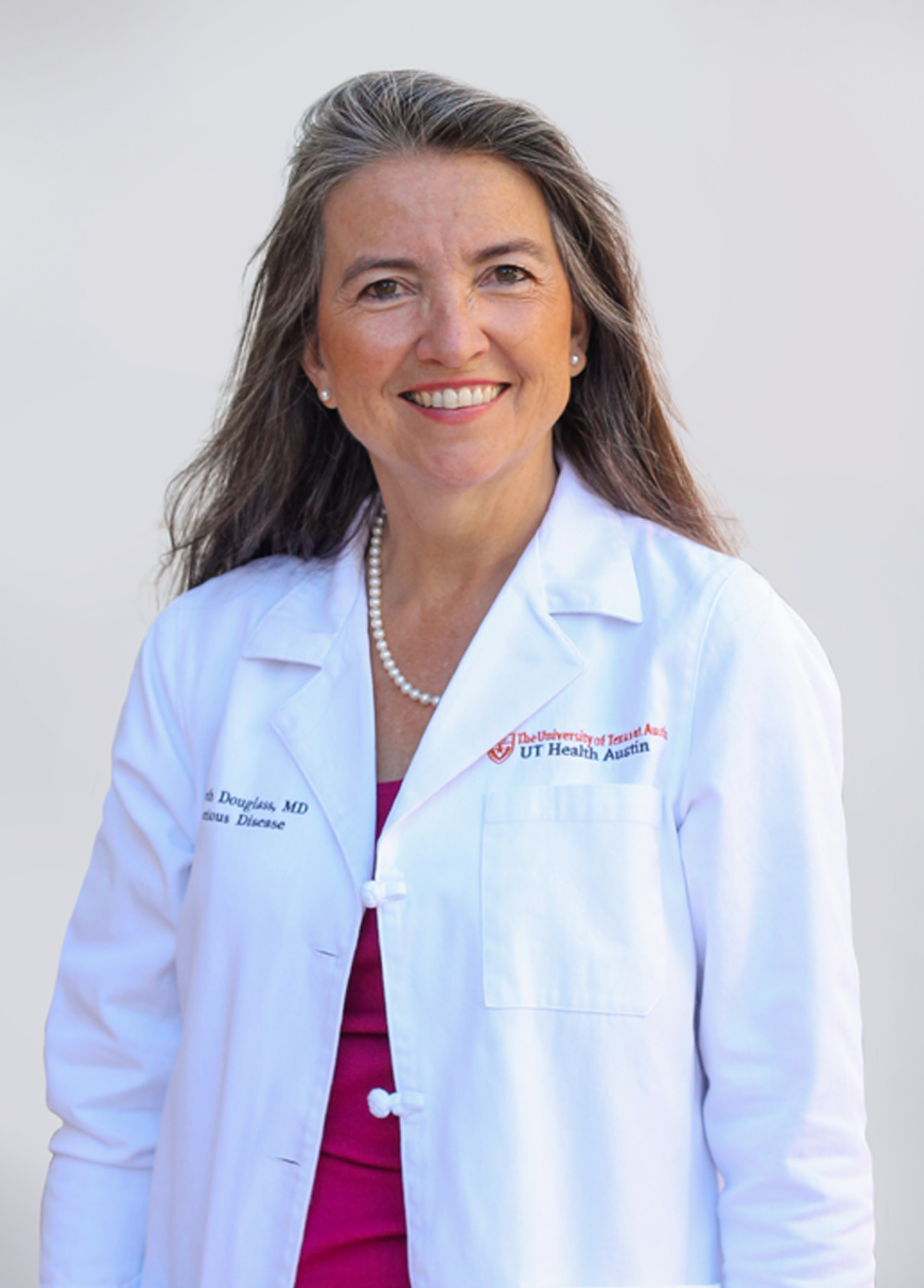 Dr. Elizabeth Douglass wearing a white coat and smiling in front of a white backdrop.