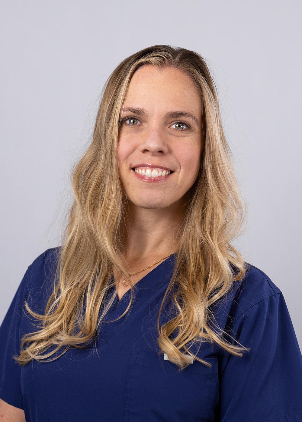 Registered nurse Emily Hutson MSN, RN, wearing navy scrubs and smiling in front of a white backdrop.