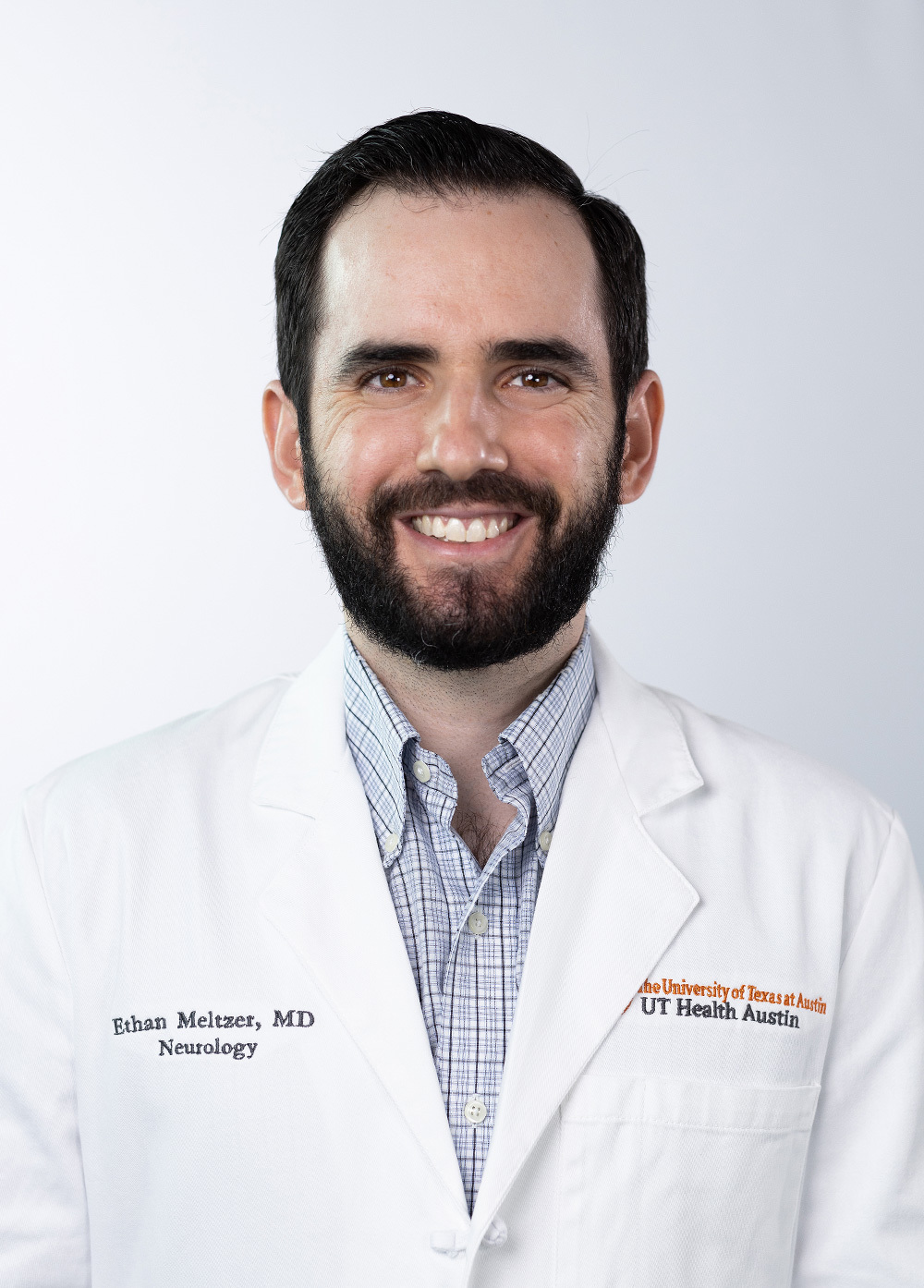 Dr. Ethan Meltzer wearing a white coat and smiling in front of a white backdrop.