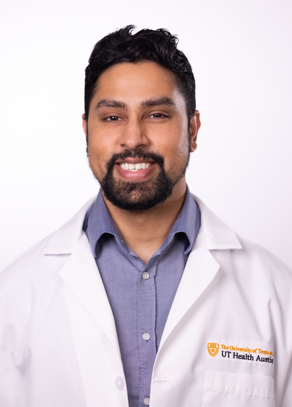 Dr. Faheem Mahomed wearing a white coat and smiling in front of a white backdrop.