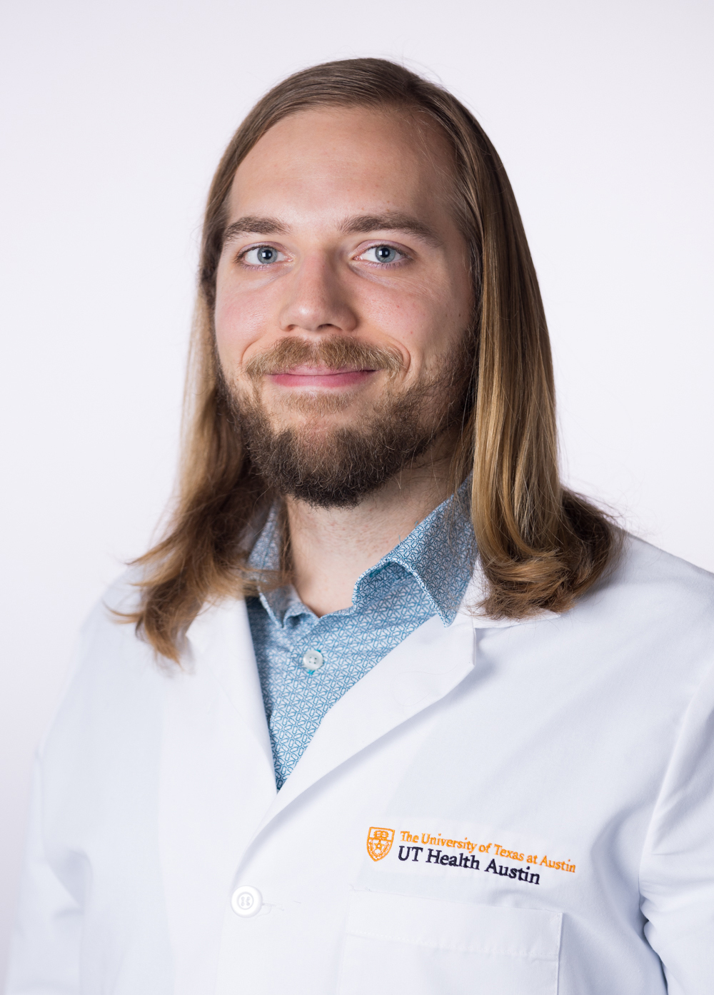 Dr. Gregory Muller wearing a white coat and smiling in front of a white backdrop.