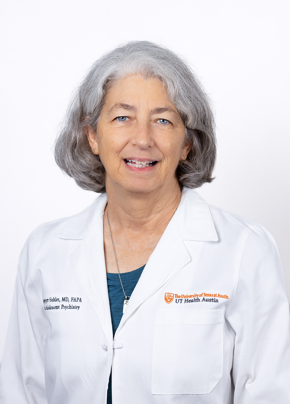 Pediatric psychiatrist Jane Ripperger-Suhler, MD, FAPA, wearing a white coat and smiling in front of a white backdrop.