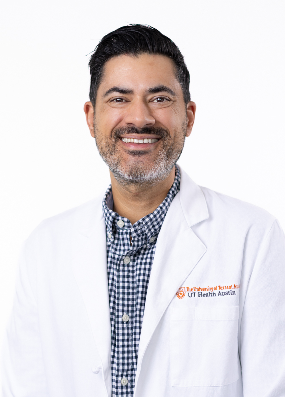 Pediatric psychologist Jeffrey Shahidullah, PhD, wearing a white coat and smiling in front of a white backdrop.