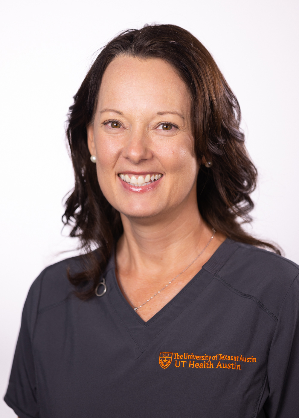 Jennifer Goertz wearing dark scrubs and smiling in front of a white backdrop.