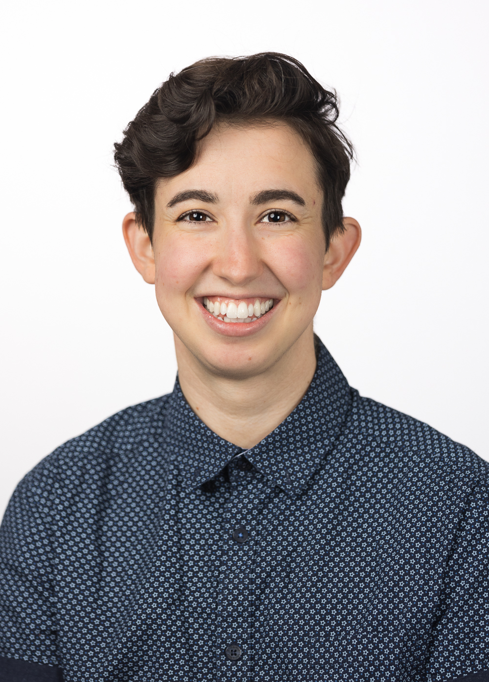 Dr. Jess Goldstein-Kral wearing a navy shirt and smiling in front of a white background.