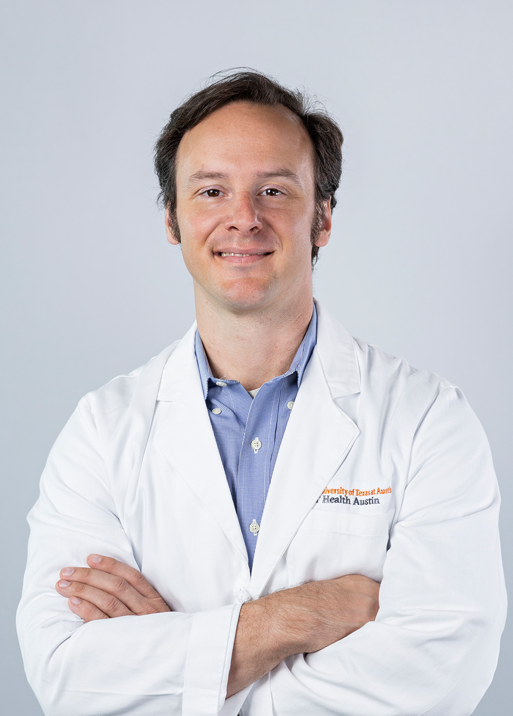 Dr. Josh Cisler wearing a white coat and smiling in front of a white backdrop.