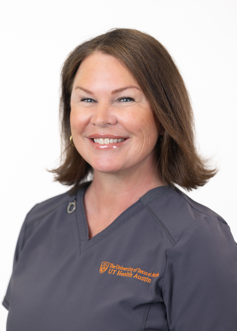 Registered nurse Julie Spurck, RN, wearing gray scrubs and smiling in front of a white backdrop.