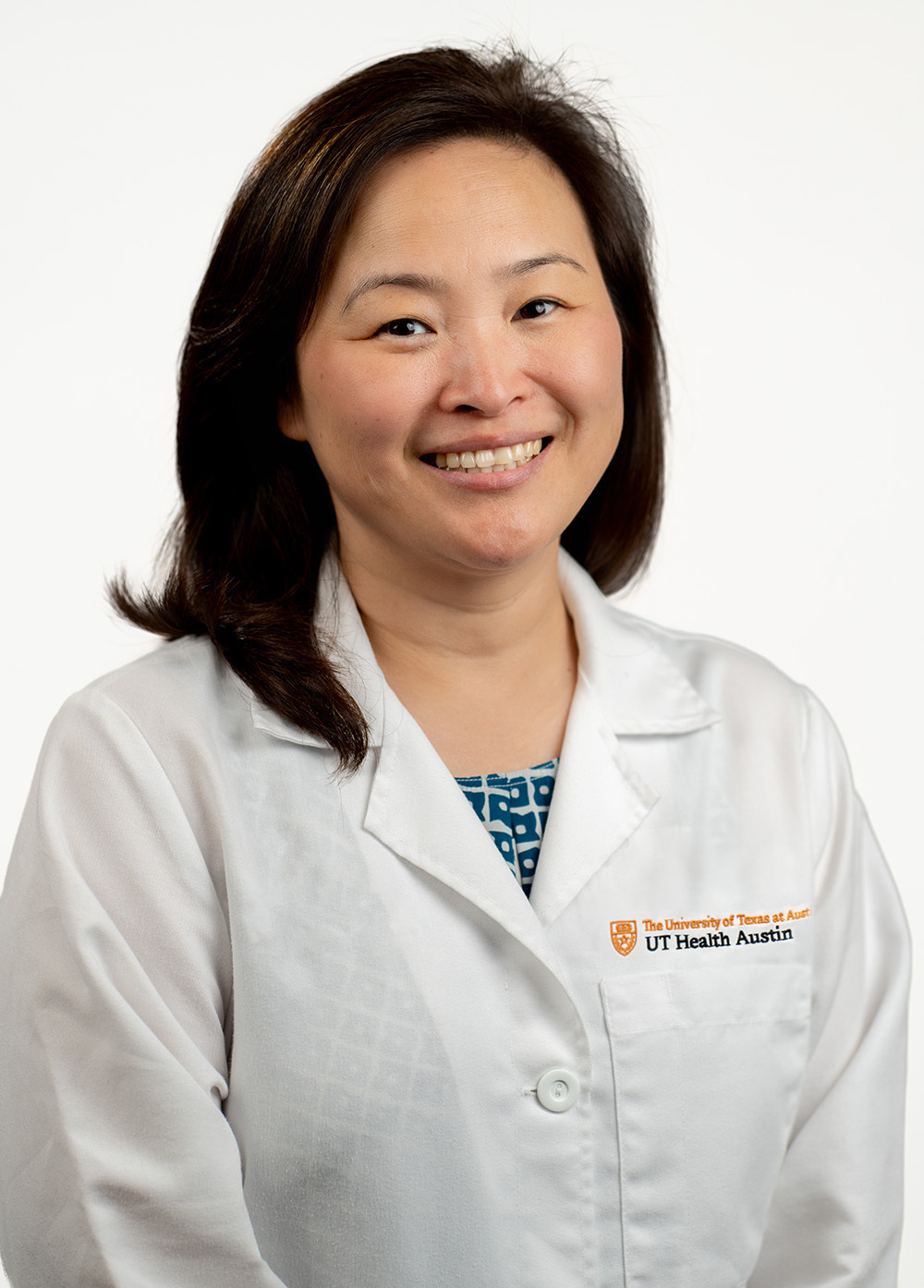 Karen Kim, MD, an adult cardiac surgeon wearing a white coat and smiling in front of a white backdrop.