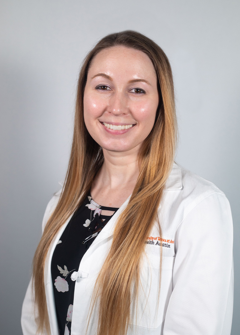 Child and adolescent psychiatrist Kari Whatley, MD, wearing a white coat and smiling in front of a white backdrop.