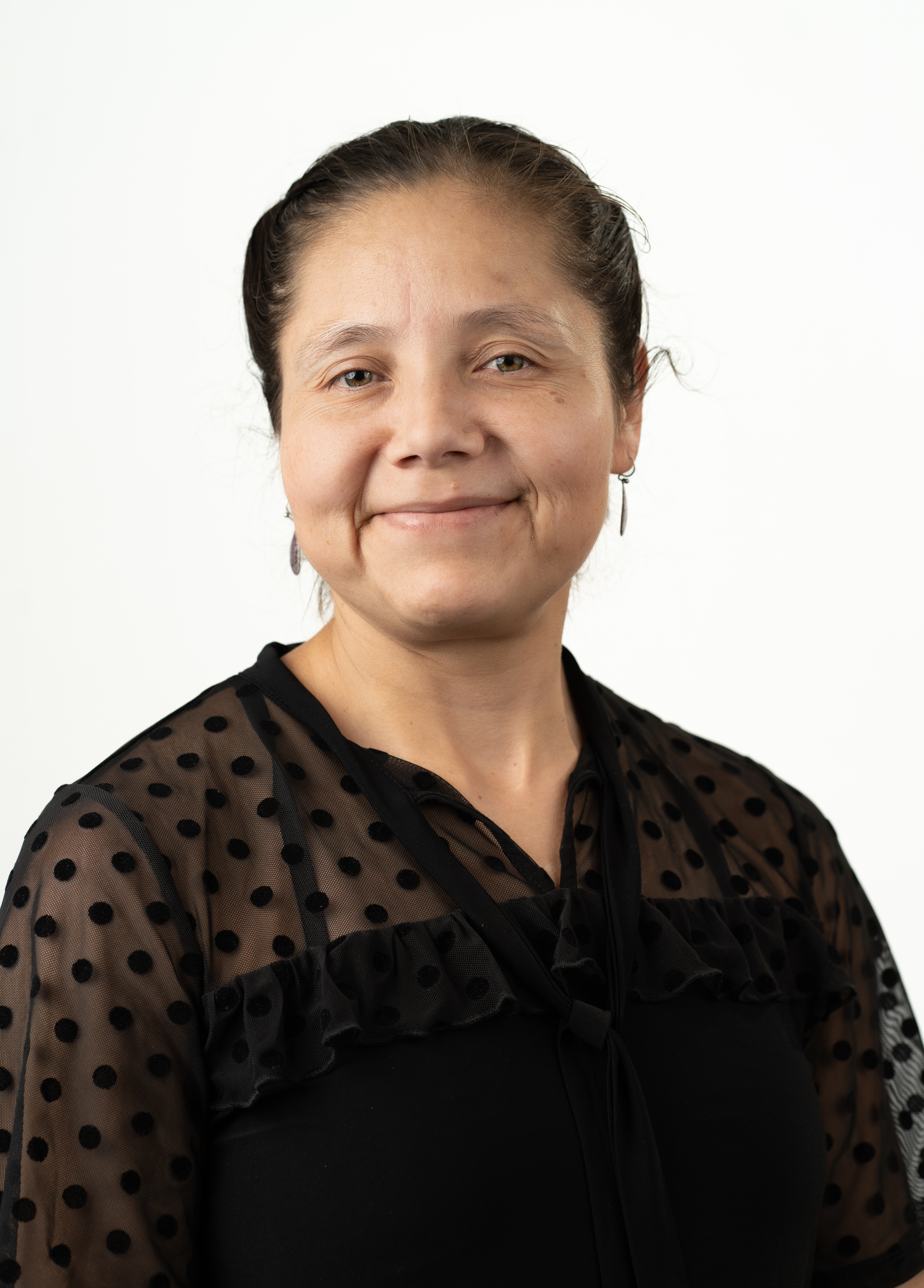 Karla Robles-Lopez, MD stands in front of a white background smiling