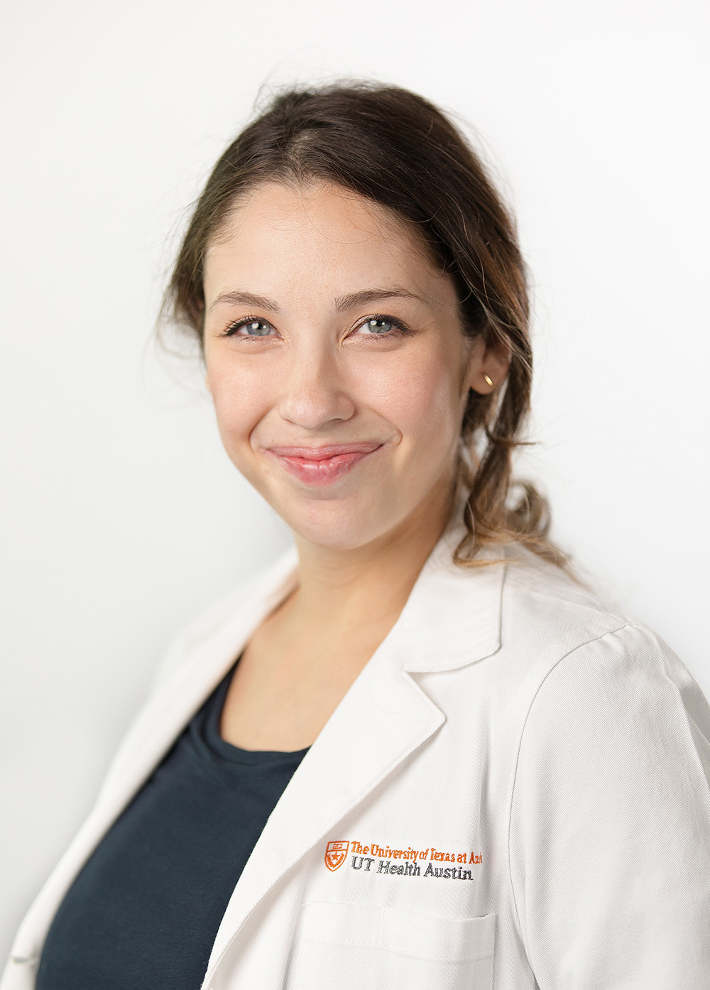 Acute care pediatric nurse practitioner Kayleigh Todd, DNP, PNP-AC/PC wearing a white coat and smiling in front of a white backdrop.