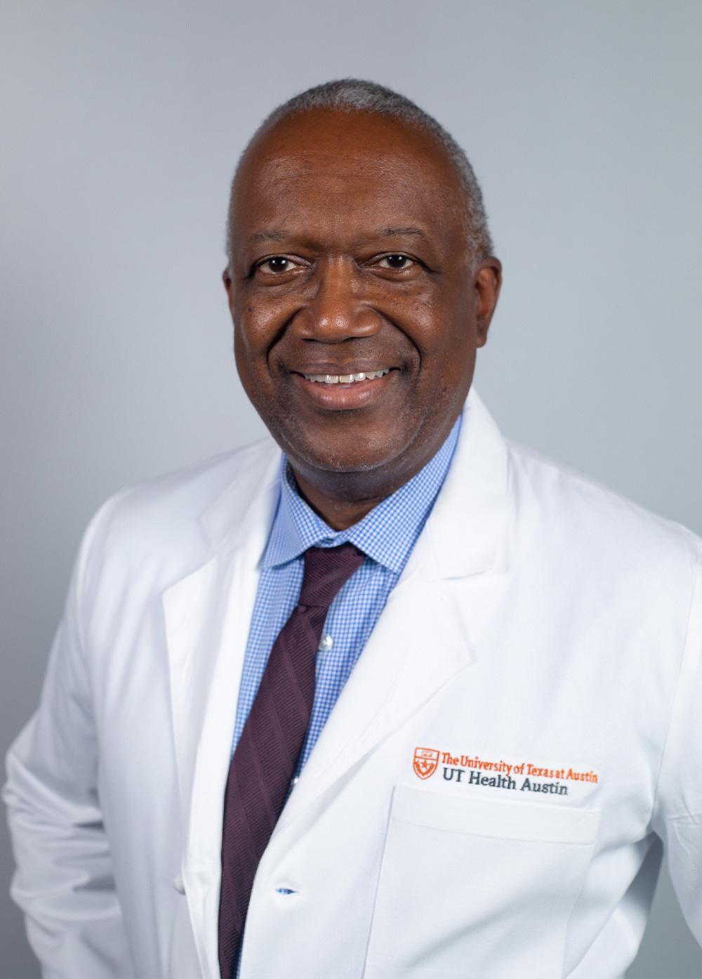 Dr. Kevin Hackshaw wearing a white coat and smiling in front of a white backdrop.