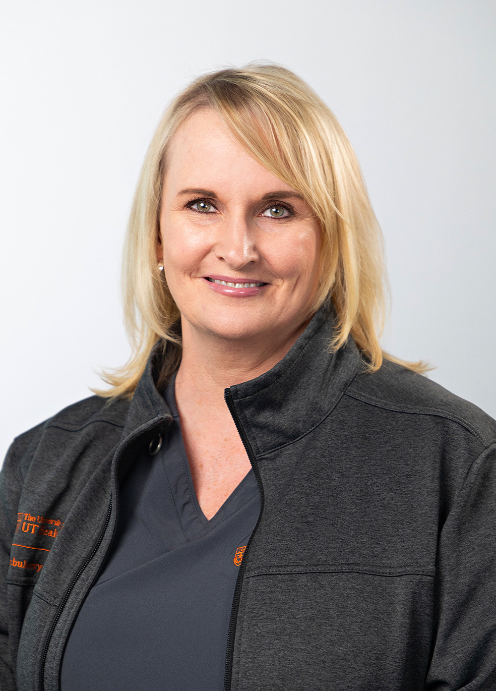 Kimberly Yarbrough wearing dark scrubs and jacket and smiling in front of a white backdrop.