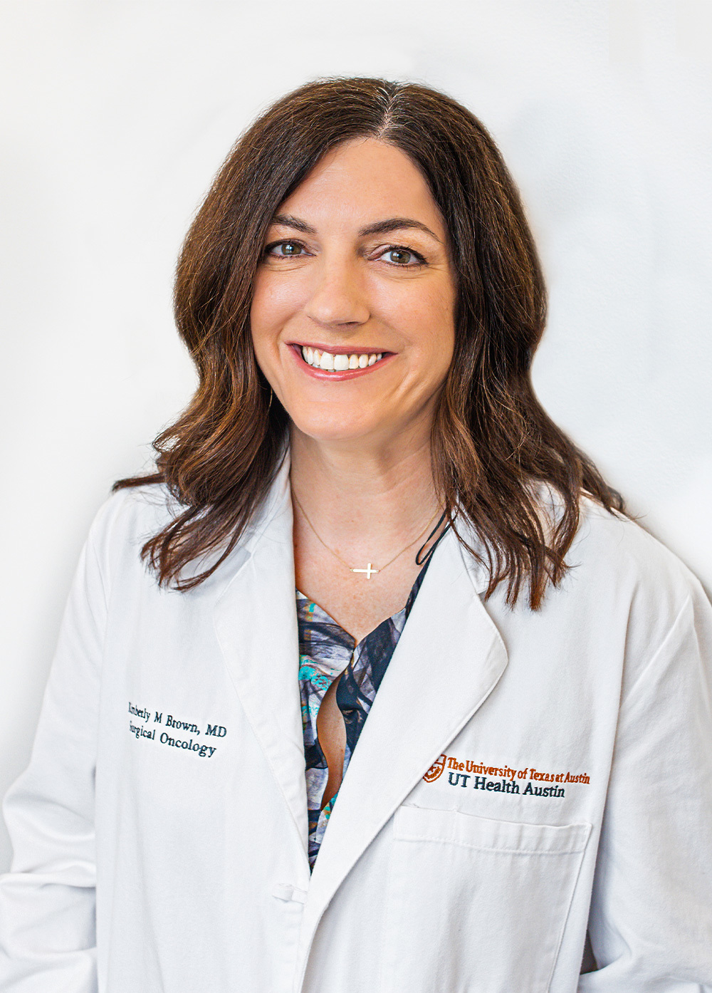 Surgical oncologist Kimberly Brown, MD, FACS, wearing a white coat and smiling in front of a white backdrop.