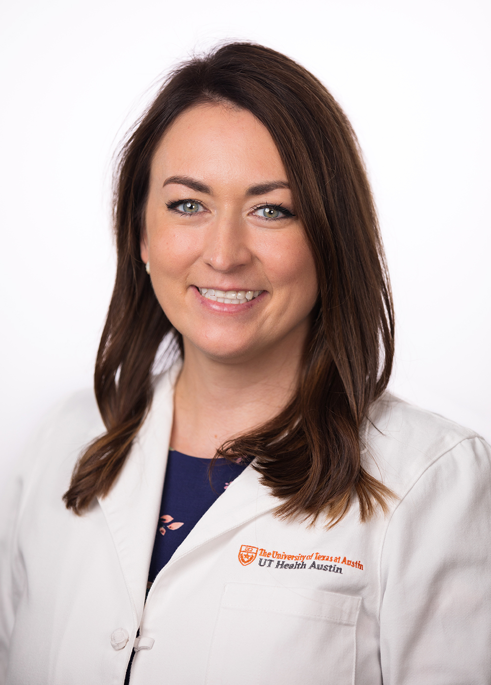 Dr. Kristen Arredondo wearing a white coat and smiling in front of a white backdrop.