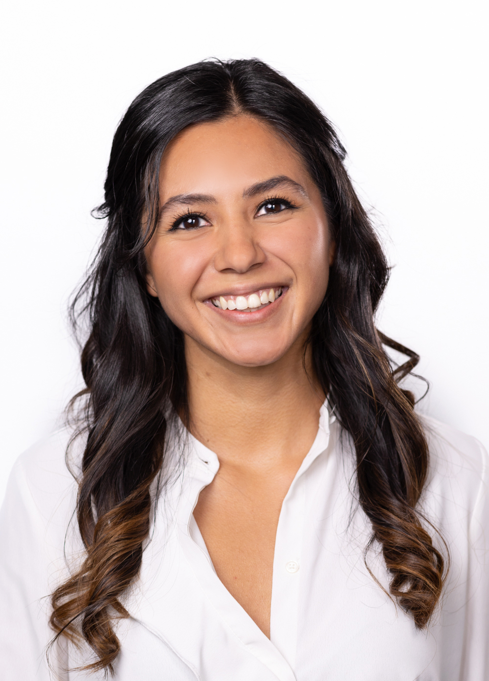 Krystal Duran wearing a white blouse and smiling in front of a white backdrop.