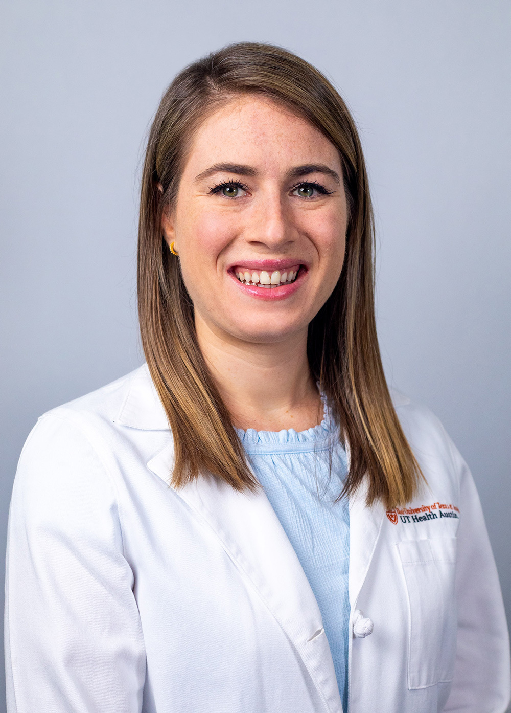 Pediatric nurse practitioner Laura Kerr, MSN, CPNP-PC, wearing a white coat and smiling in front of a white backdrop.