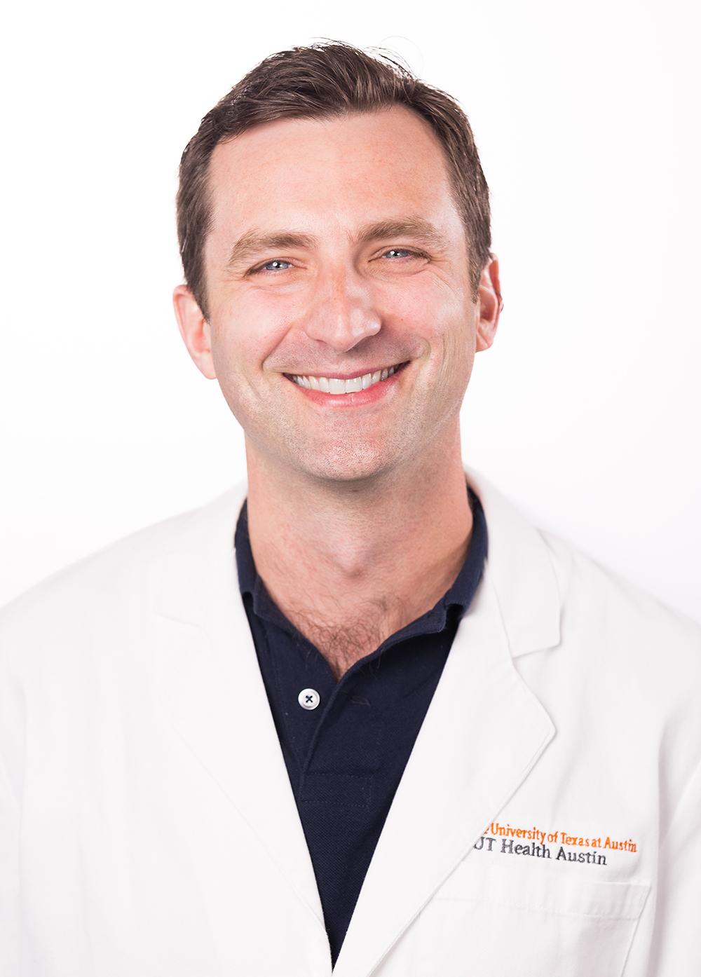 Dr. Lief Fenno wearing a white coat and smiling in front of a white backdrop.