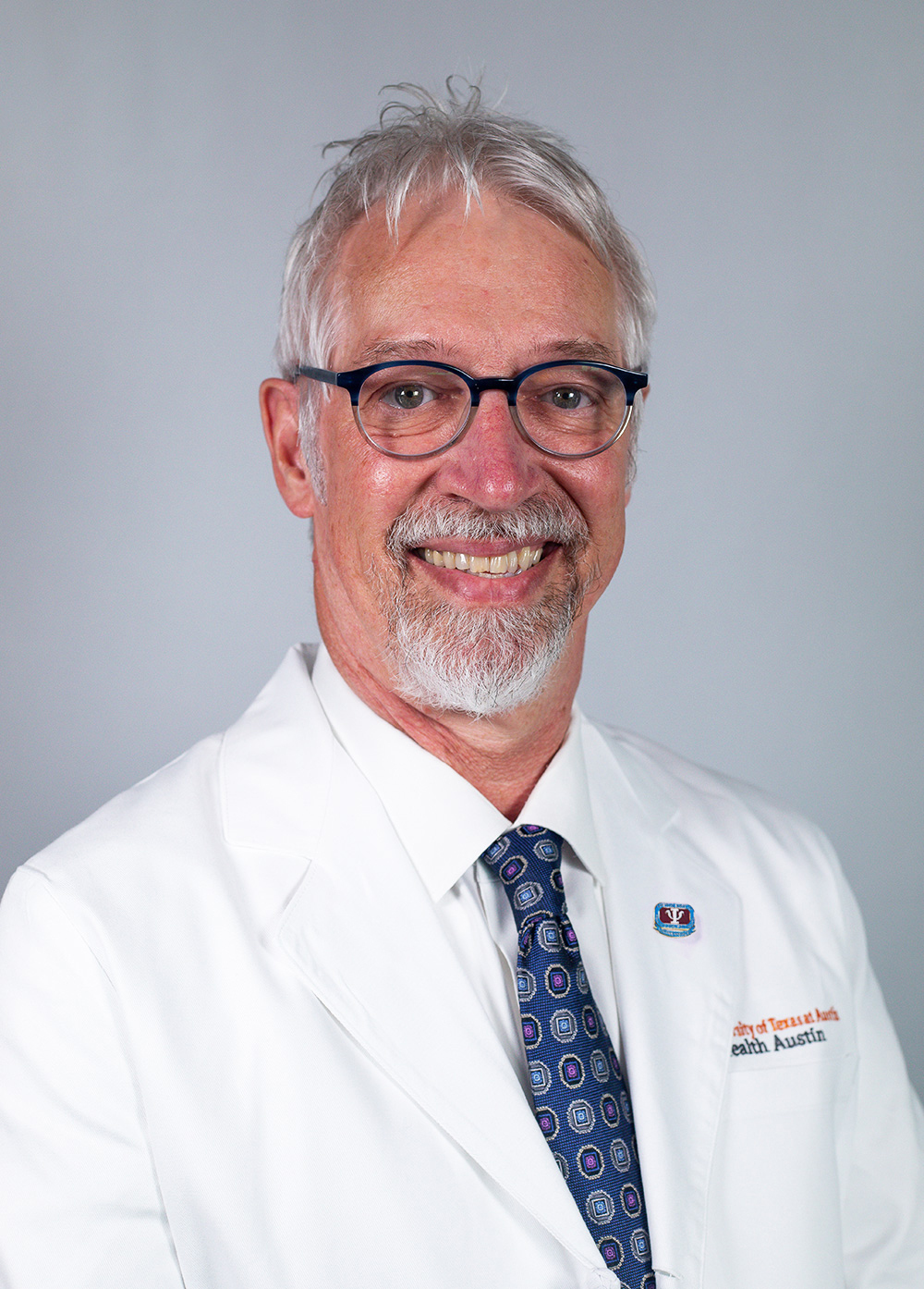 Dr. Lloyd Berg wearing a white coat and smiling in front of a white backdrop.