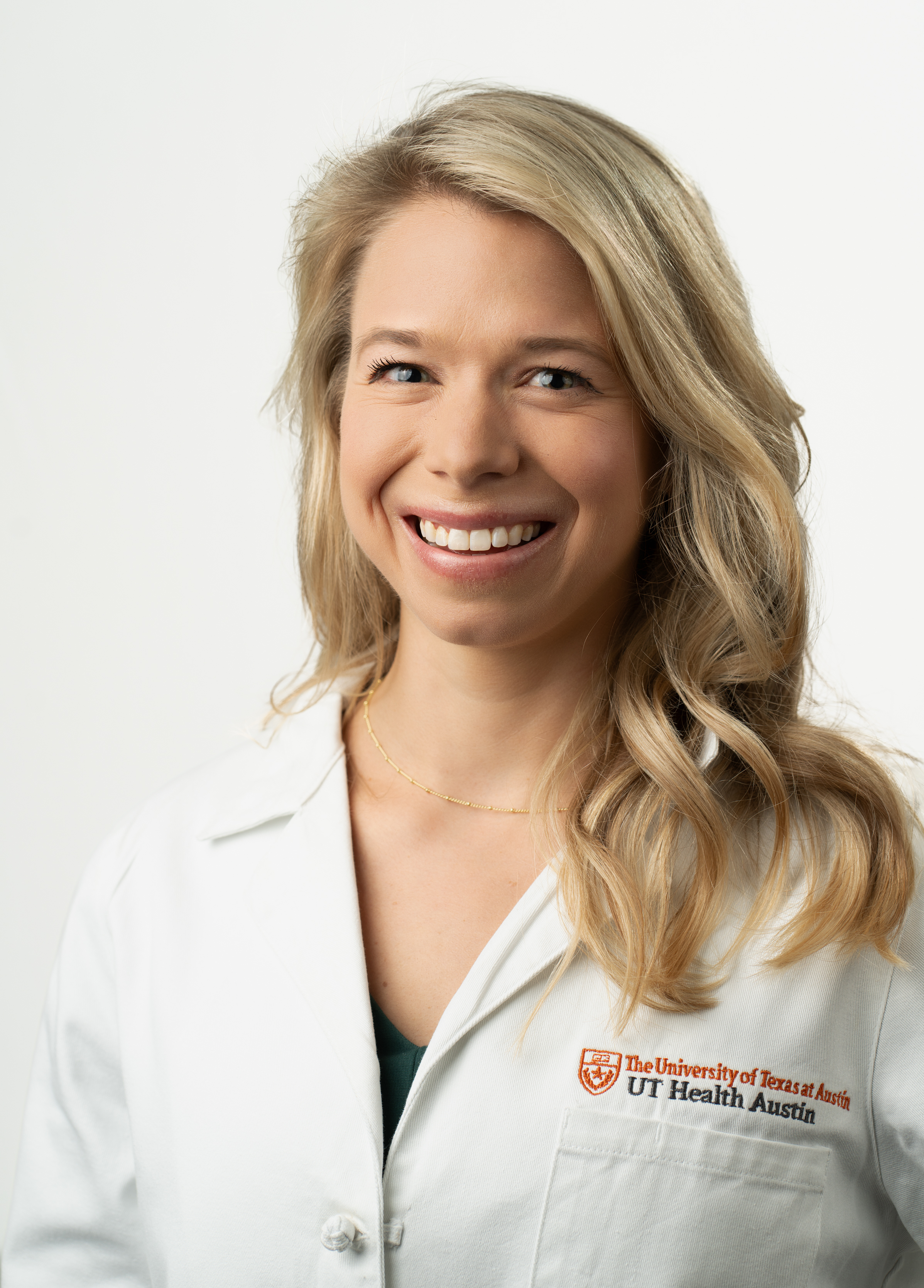 Pediatric nurse practitioner Margaret “Maggie” Goss, MSN, CPNP-PC wearing a white coat and smiling in front of a white background.