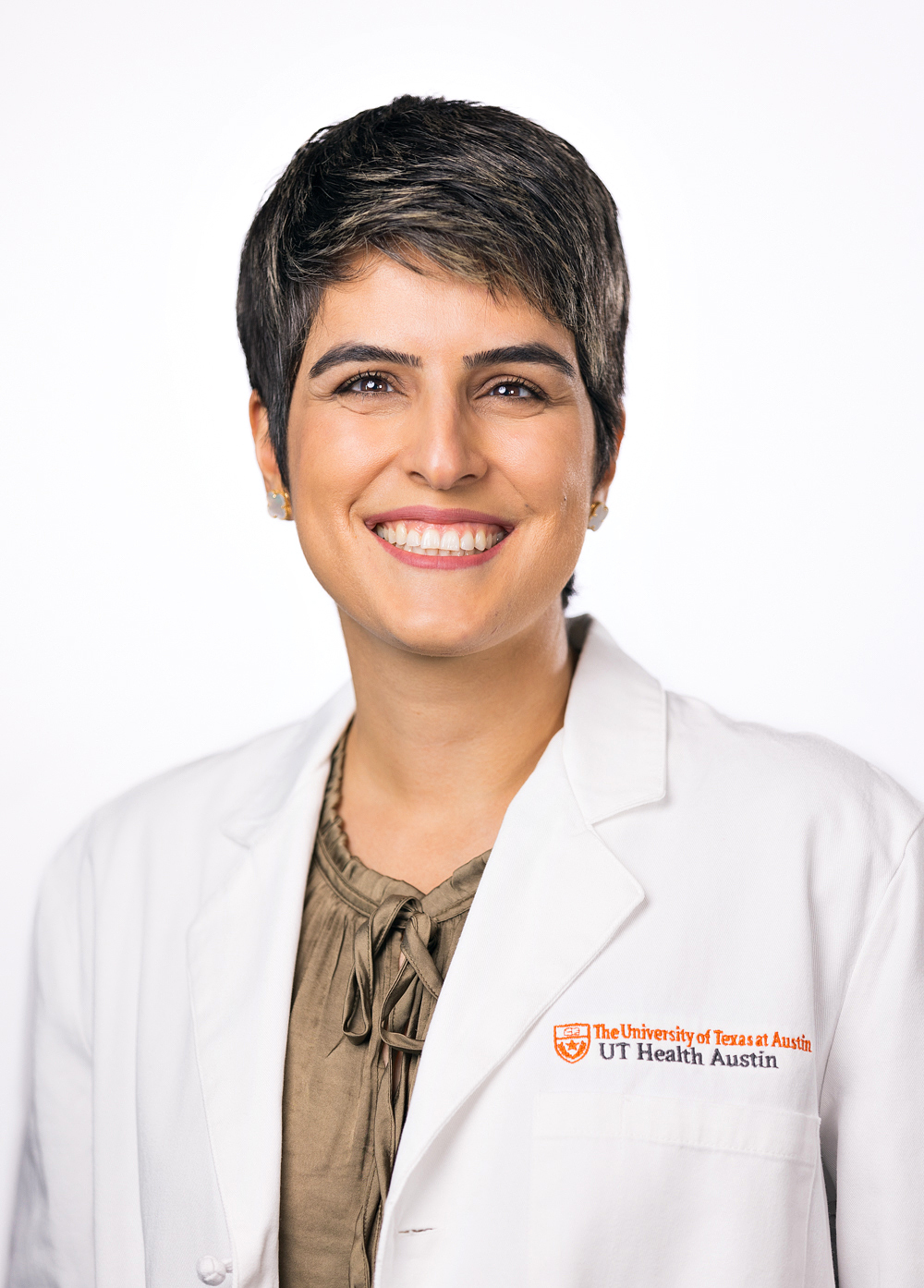 Dr. Mahsa Mansouri wearing a white coat and smiling in front of a white backdrop.