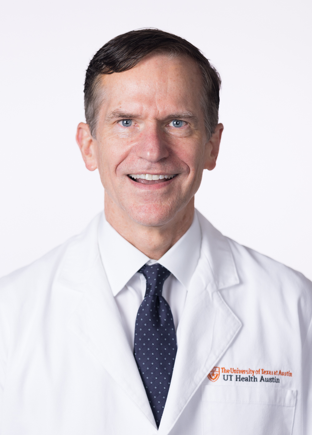 Dr. Mark Townsend wearing a white coat and smiling in front of a white backdrop.