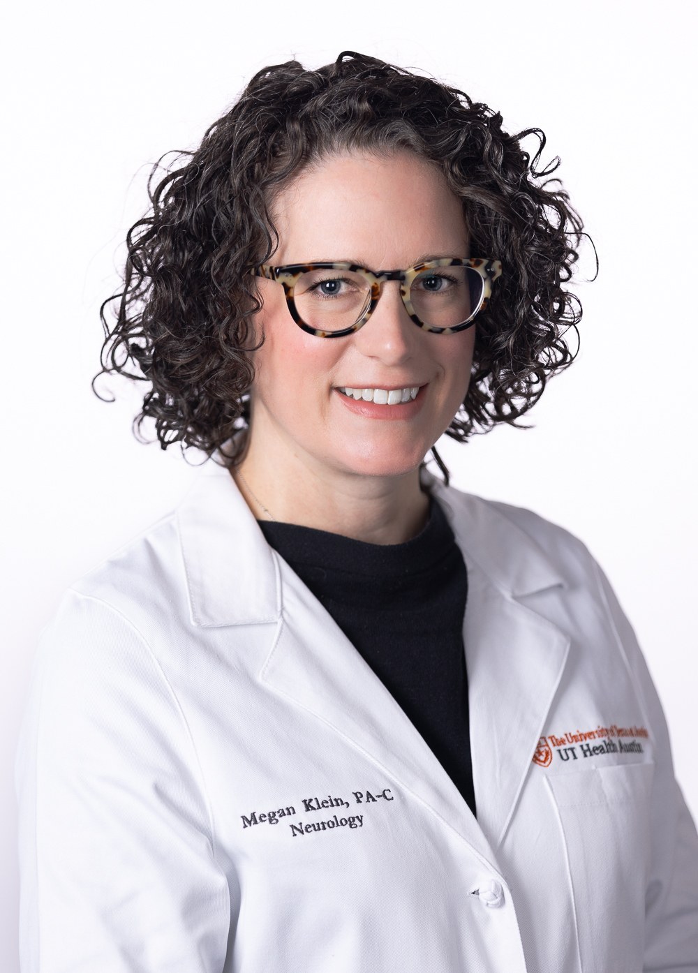 Megan Klein wearing a white coat and smiling in front of a white backdrop.