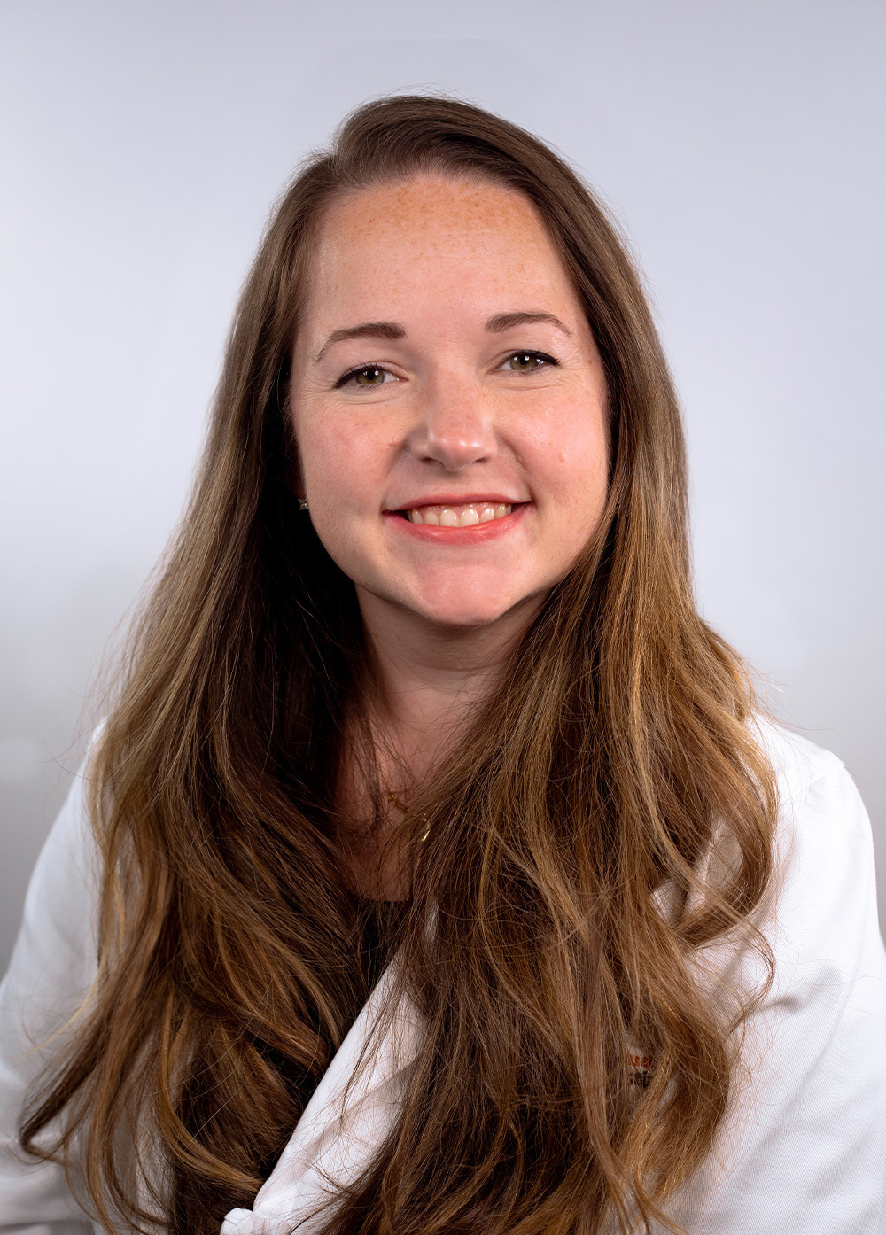 Pediatric nurse practitioner Michelle McCartney, MSN, BSN, APRN, CPNP-PC wearing a white coat and smiling in front of a white backdrop.