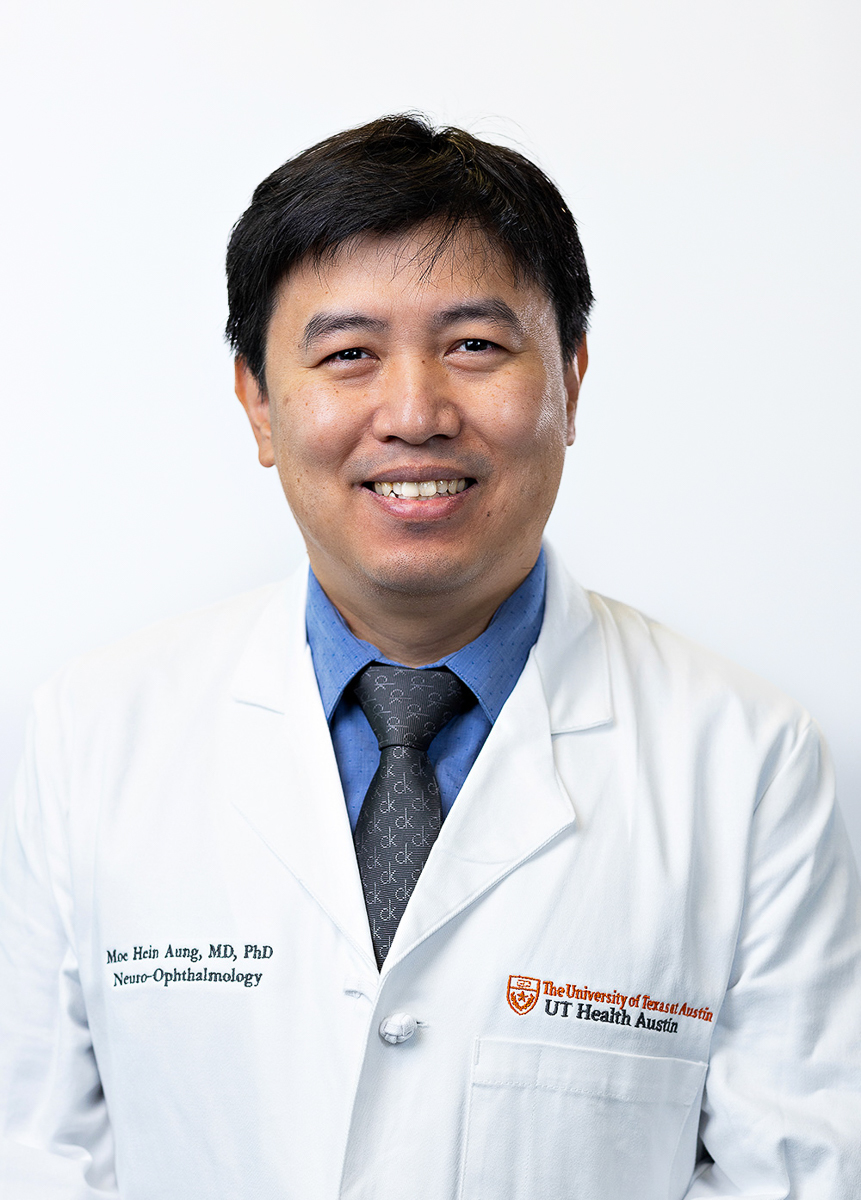 Neuro-ophthalmologist Moe “Harry” Hein Aung, MD, PhD, wearing a white coat and smiling in front of a white backdrop.