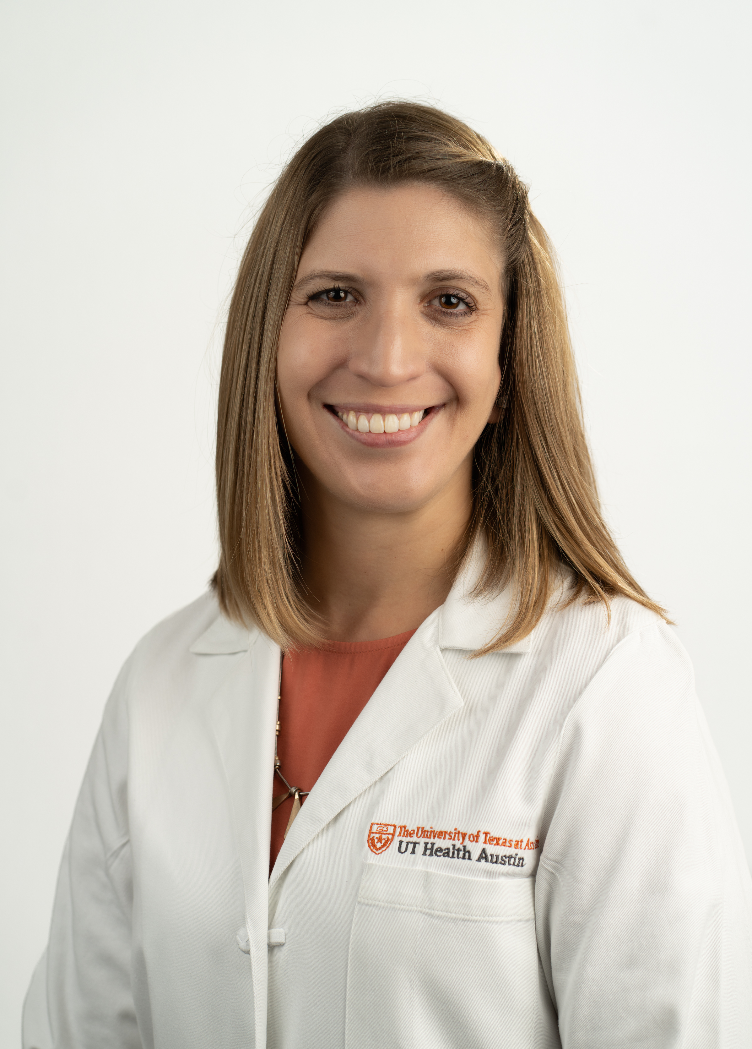 Pediatric nurse practitioner Natalie Beimel, MSN, APRN, CPNP-AC, wearing a white doctors coat and smiling in front of a white backdrop.