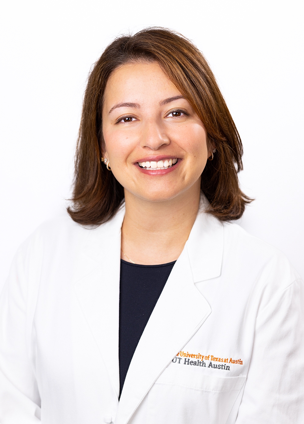 Dr. Noor Zwayne wearing a white coat and smiling in front of a white backdrop.