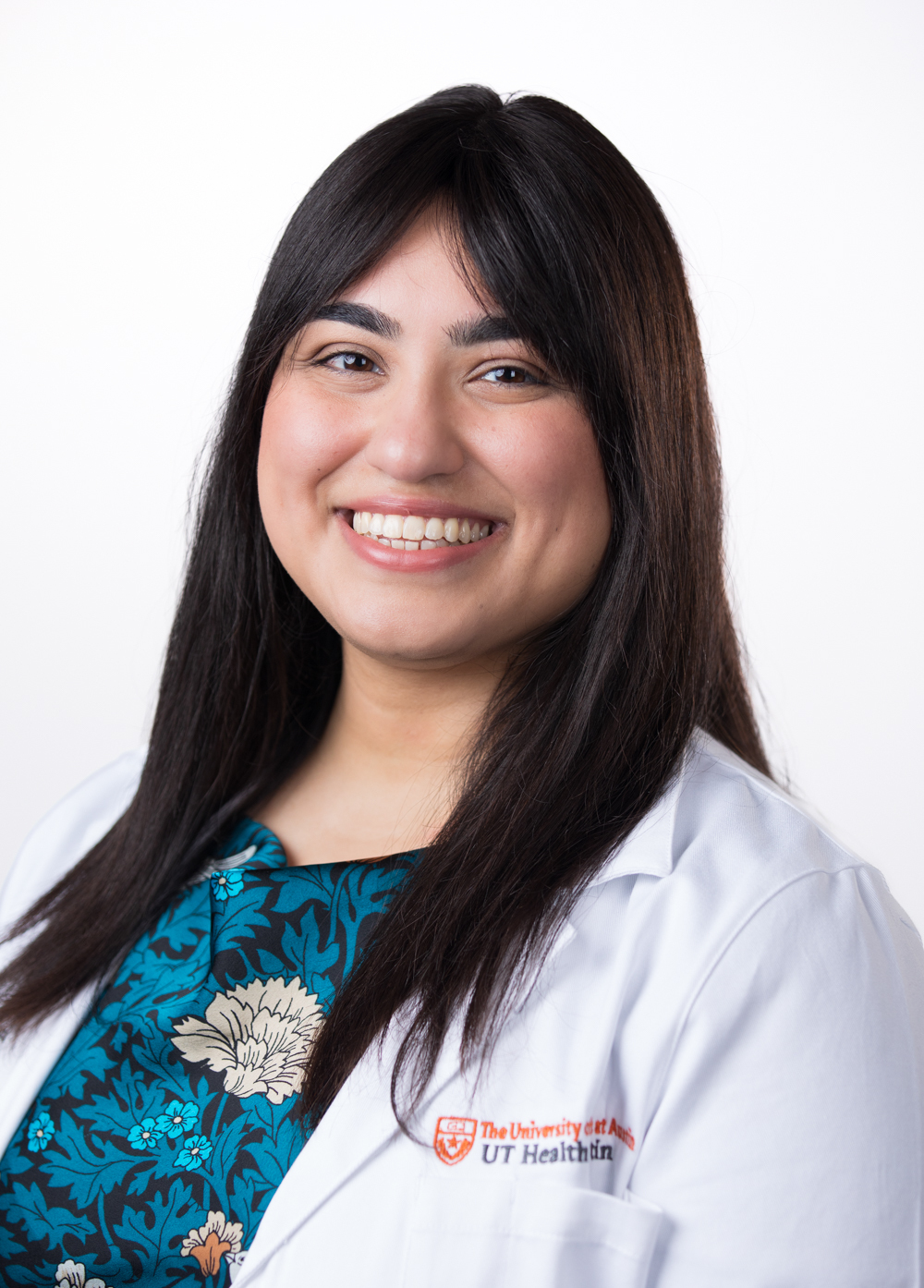 Board-certified psychiatrist Priya Kumar-Kaparaboyna, MD, wearing a white coat and smiling in front of a white backdrop.