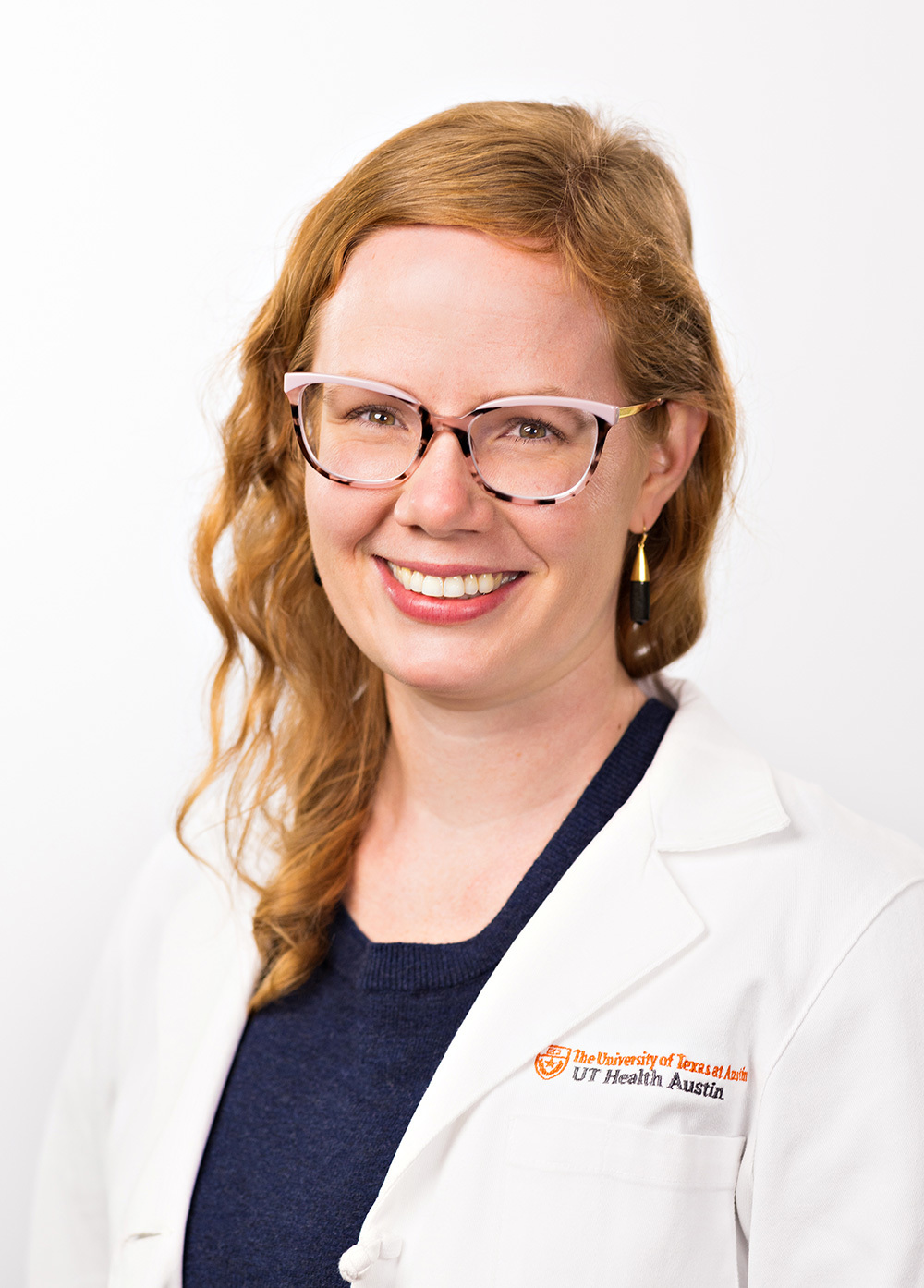 Rachel Alhanti wearing a white coat and smiling in front of a white backdrop.