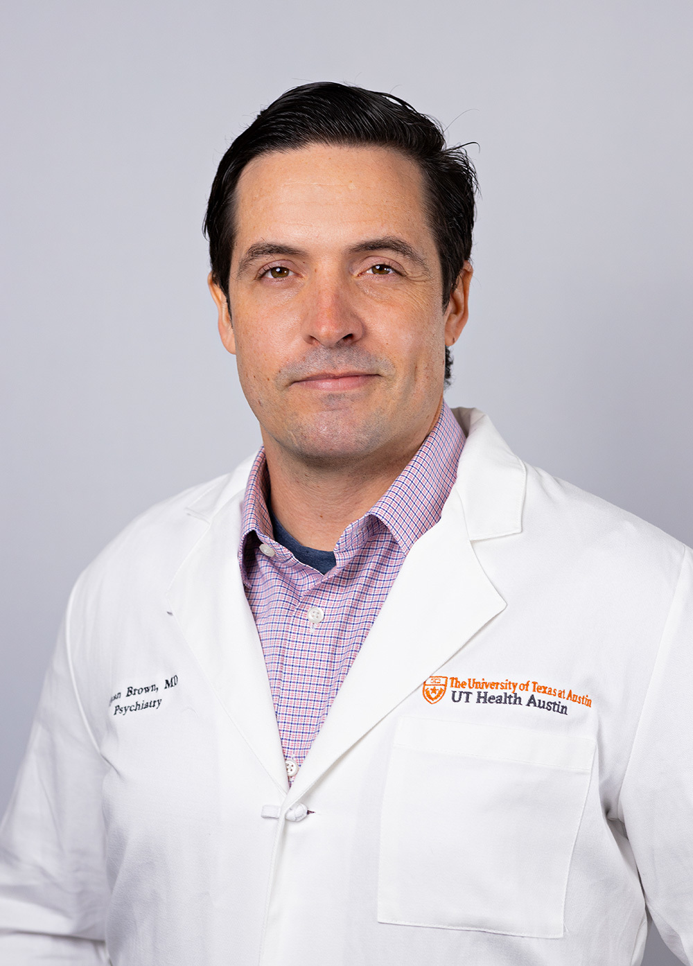 Pediatric psychiatrist Ryan Brown, MD, wearing a white coat and posing in front of a white backdrop.