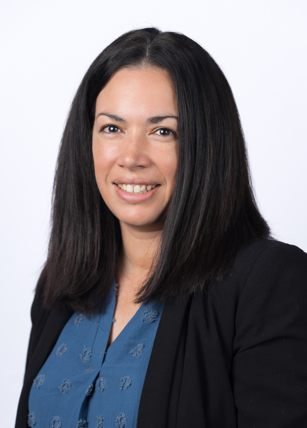 Sara Green-Otero, LCSW, wearing a black blazer and teal blouse and smiling in front of a white background.