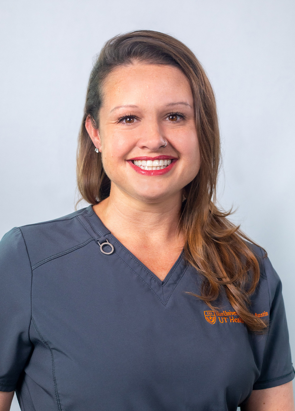 Sarah Hunsaker wearing dark scrubs and smiling in front of a white backdrop.