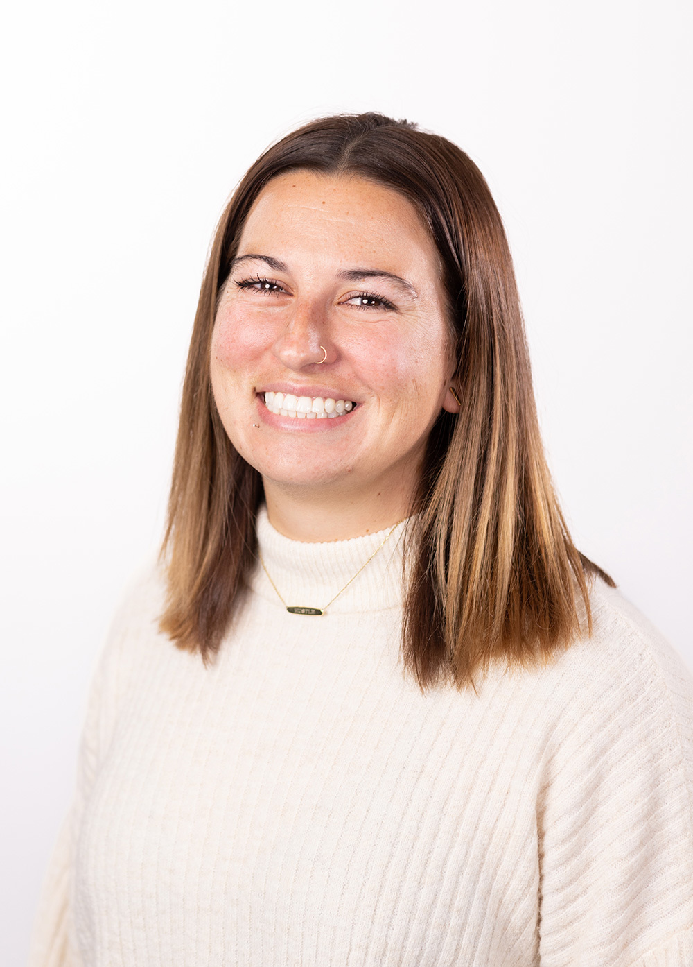 Shandalene Ghanem wearing a cream colored sweater and smiling in front of a white backdrop.