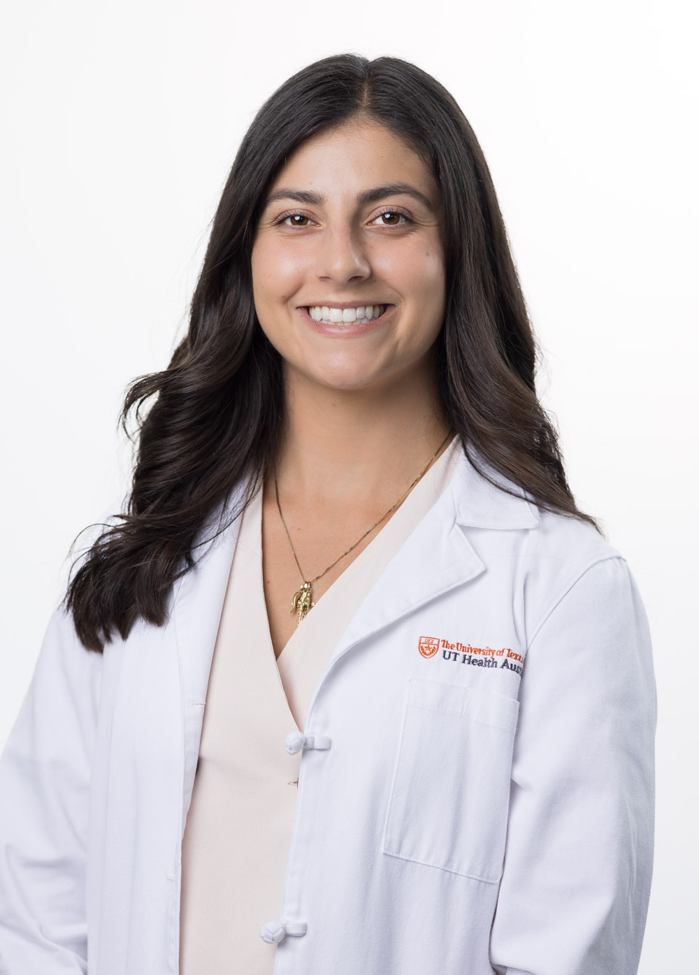 Sofia Silvestri is looking at the camera and smiling. She is wearing a white coat and a beige blouse.