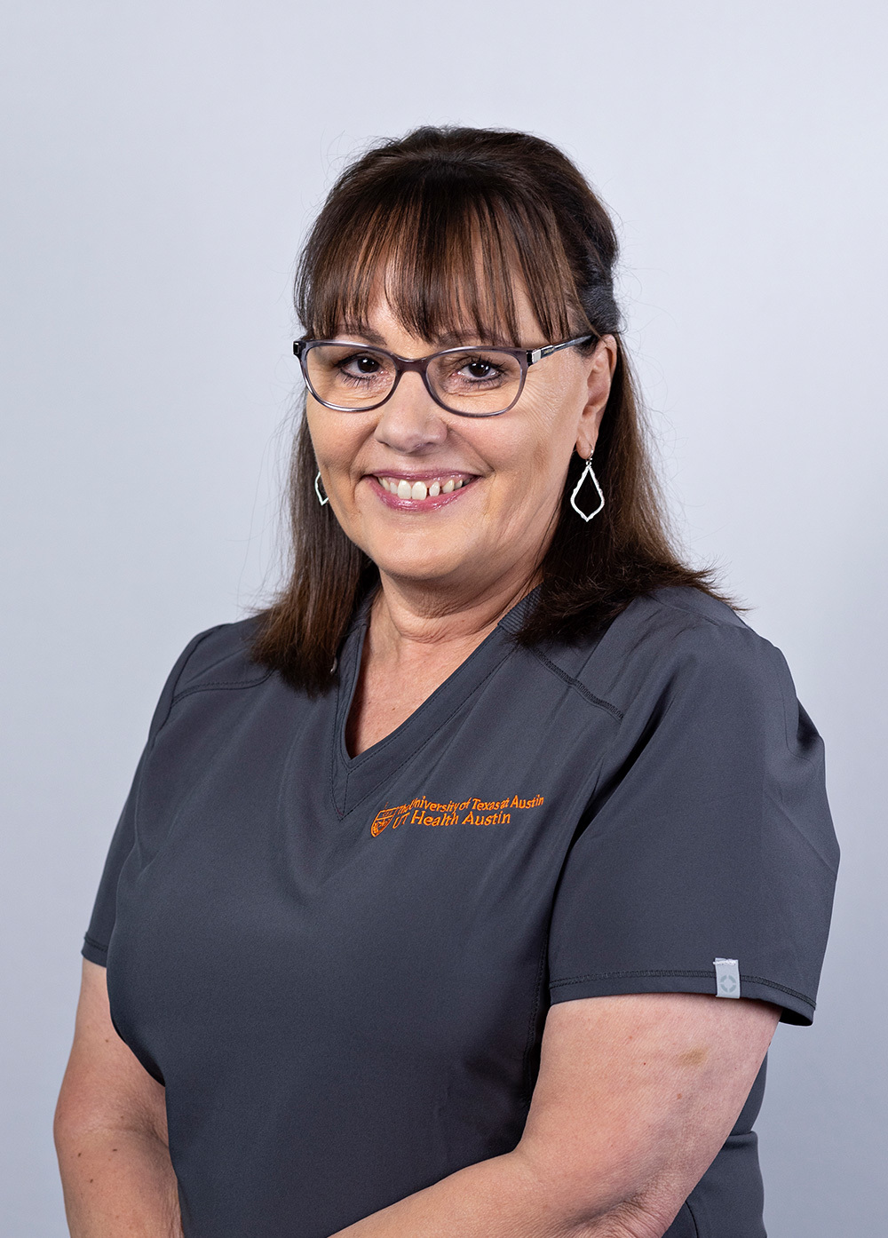 Terri Stuchl wearing dark scrubs and smiling in front of a white backdrop.