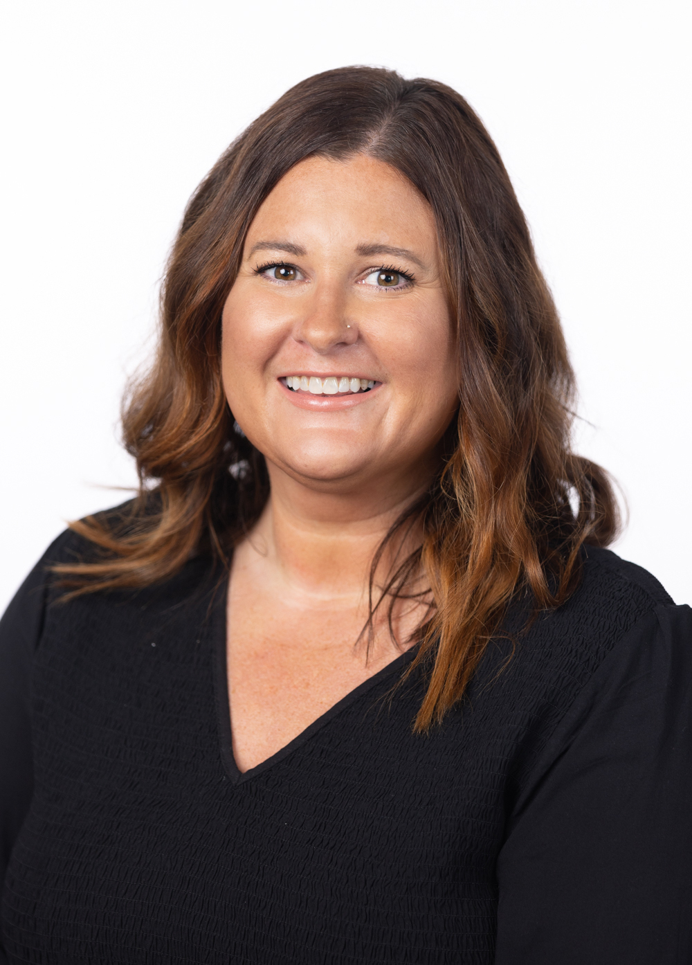 Social worker Tiffany Sizemore, LCSW, smiling in front of a white backdrop. She is wearing a black shirt and has brown hair.