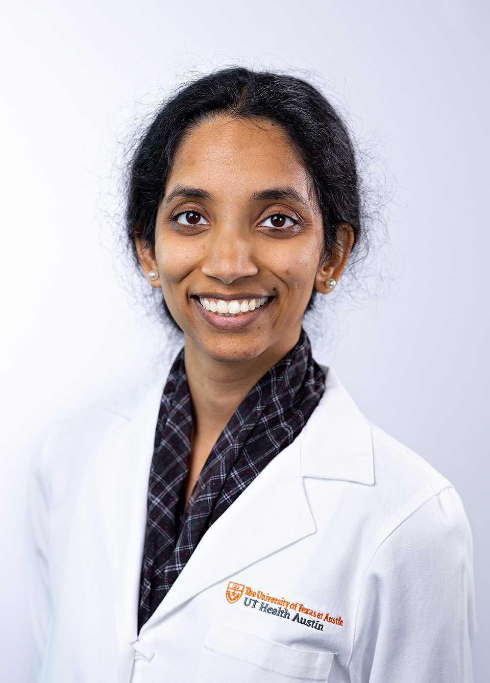 Pediatric neurologist Vandana Vedanarayanan, MD, wearing a white coat and smiling in front of a white backdrop.