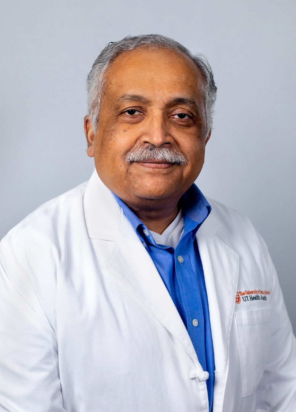 Pediatric neurologist Vettaikorumakankav Vedanarayanan, MD, FRCPC, wearing a white coat and smiling in front of a white backdrop.