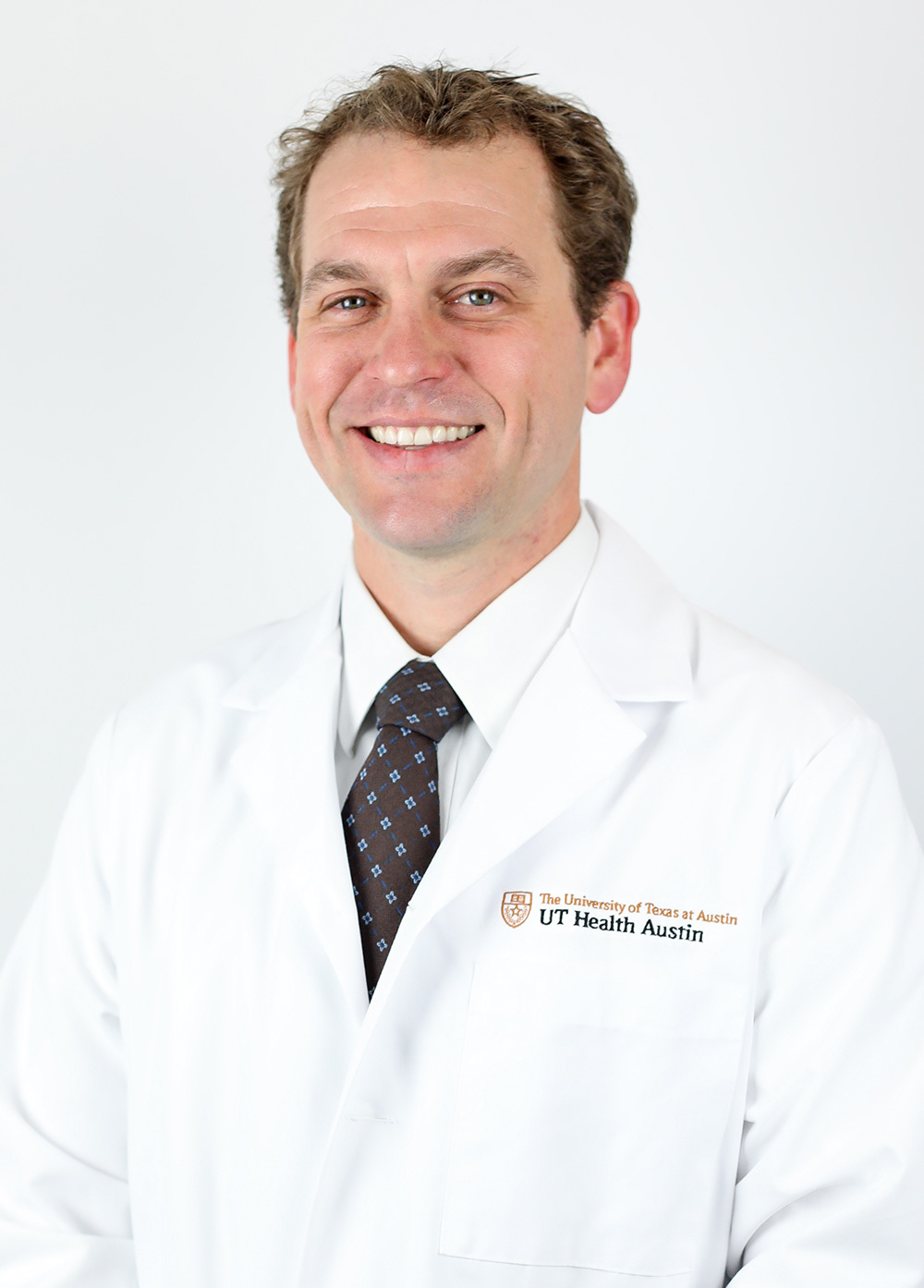 Dr. Garrett Key wearing a white coat and smiling in front of a white backdrop.