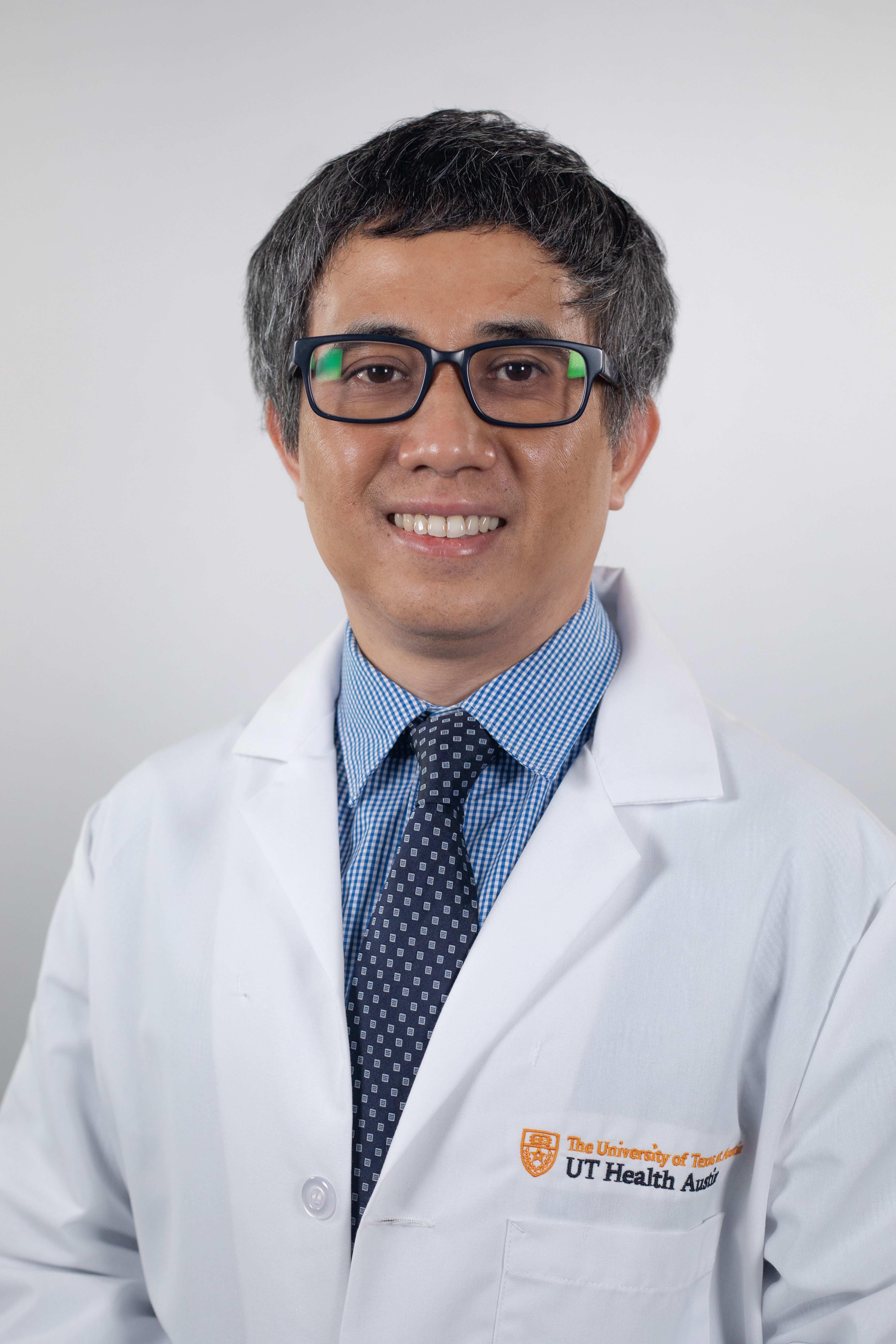 Dr. Kyaw Lwin Aung wearing a white coat and smiling in front of a white backdrop.